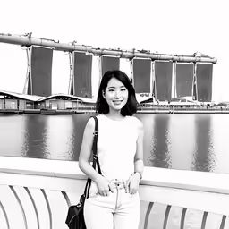 a young woman standing at the top of a hill with a bridge in the background