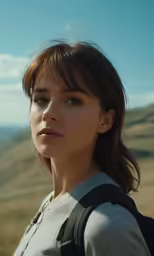 young woman wearing grey shirt standing in open field