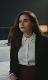 a woman in a white shirt and black blazer looking to her left