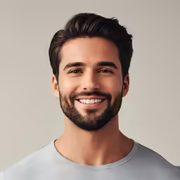 a smiling young man with beard and grey shirt