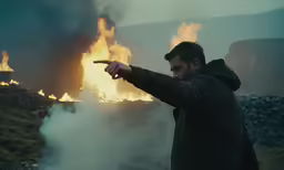 a person pointing a finger in front of a fire
