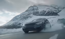 a car driving in the snow on a road near mountains