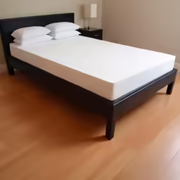 an unmade bed on a wood floor with white pillows