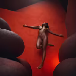 a naked woman laying on top of a red rug