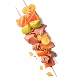 assortment of meats and vegetables on skewers on white