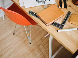 a table with some rulers and a book on it,desk with notebooks and rulers on wooden table top