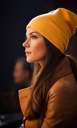 a woman wearing a yellow beanie in front of a dark background