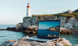 a lap top sitting on a rock by the ocean