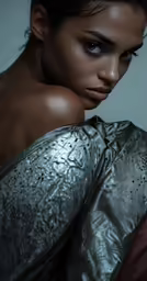 a young woman with a silver shirt and black eyeliner