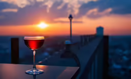 a wine glass filled with red liquid and next to a view