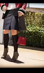 woman wearing skirt, jacket and boots with purse