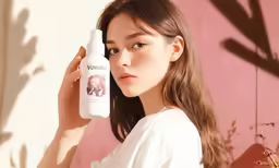 a woman with long hair holding a bottle of hair care product