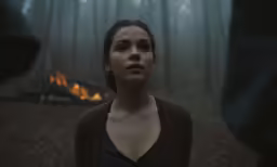 woman staring up in dark, smokey, and misty woods