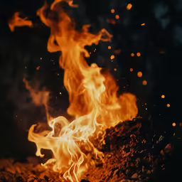 flames burning over rocks and grass on a night sky