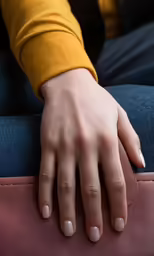 someones hand resting on the couch near a persons lap