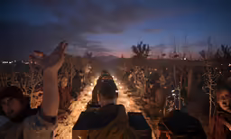people in the field sitting with lighted candles