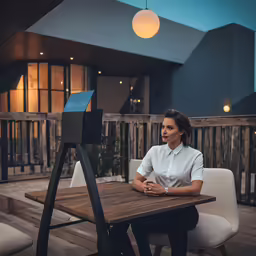 a woman is sitting at a wooden table with her laptop open