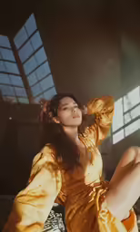 a woman sitting on a bed in a yellow dress