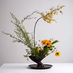 a black vase holding different flowers on top of a table