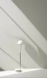 a lamp is sitting on a desk, casting long shadows