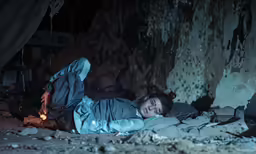 a person laying in a dark cave with his arms outstretched
