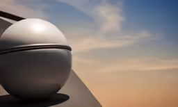 a shiny sphere sculpture on the side of a building
