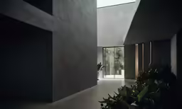 a concrete wall and hallway in a room with large windows