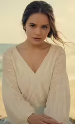 a woman sitting on the beach near the water