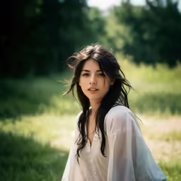 a woman wearing a white blouse sits in the grass