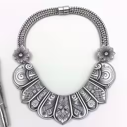 a pen is next to an ornate design,an artistically designed silver necklace on display next to a pen
