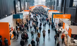 a large group of people are milling around at a trade event