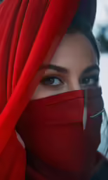 the woman with blue eyes has a red veil over her face