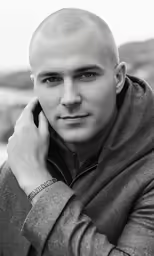 a man posing for the camera holding a phone to his ear