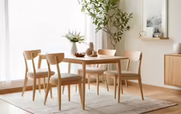the large wooden table has four chairs and a vase with a flower on it