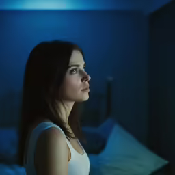 a woman is looking off into the distance in a dark room