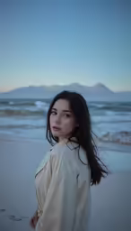 a young woman standing on a beach with her arms behind her head