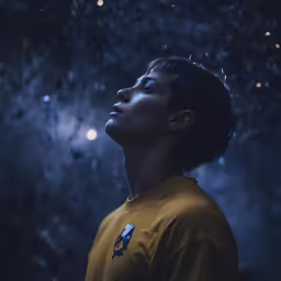a young man looking up into the sky at stars