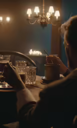 a person sitting at a table with cups and a mug