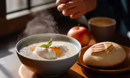 a bowl of soup with a bowl of bread next to it