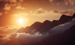 a photo of the sun setting in between mountains