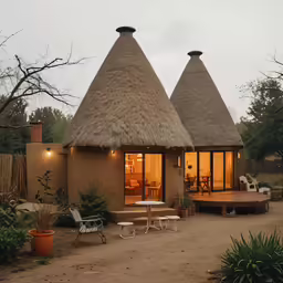 two houses with a straw thatched roof are lit up