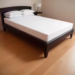 a white mattress with black headboard in a bed room