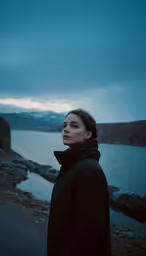 a woman in black standing next to a body of water