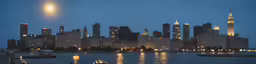 a city in the distance at night with lights reflecting on the water