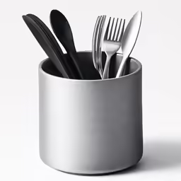 a cup filled with forks and knives on top of a table