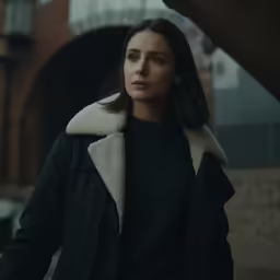 a woman with a shearl collar is in front of a building