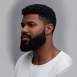 a black man wearing a beard standing in front of a gray wall