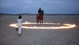 two women ride horses and appear to be surrounded by flames