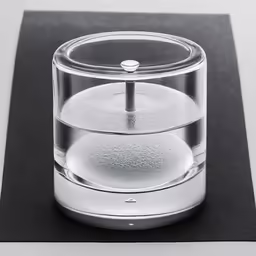 a small glass container sitting on top of a black surface