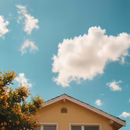 a yellow house under a blue sky with clouds